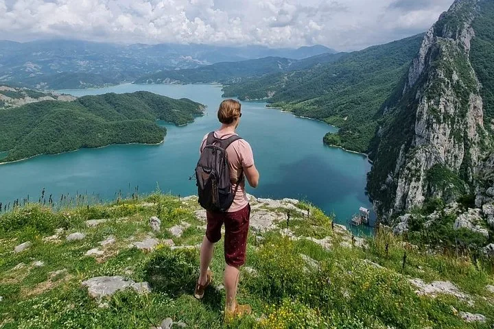 Ein Mann steht am grasbewachsenen Rand einer Klippe mit Blick auf den Bovilla-See.